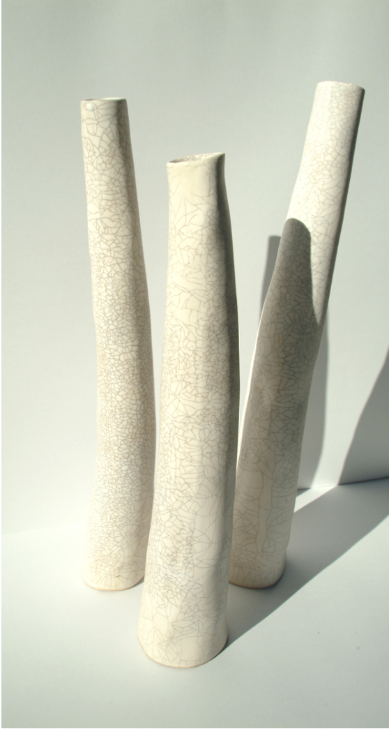 Collection of tall slender ceramic vessels with elegant crackle glaze finish in cream and beige tones, showcasing organic textural patterns and sculptural forms