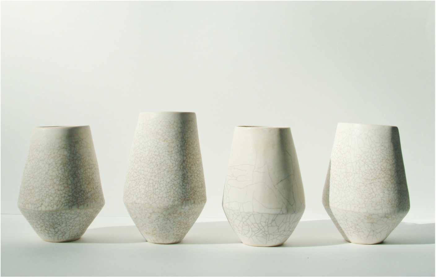 Four ceramic vessels with subtle crackle glaze finish in neutral tones, demonstrating variations in crackling patterns and organic texture